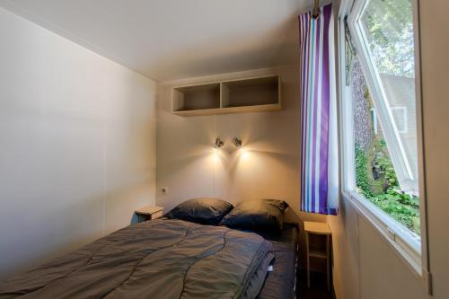 une petite chambre avec un lit et une fenêtre dans l'établissement Mobilhome 6 personnes climatisé, à Saint-Martial-de-Nabirat