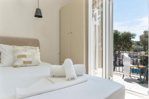 a white bedroom with a bed and a balcony at Ilias Voula Studios in Panormos Kalymnos