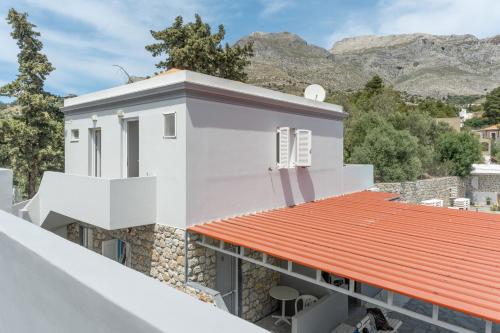 a white house with an orange roof with mountains in the background at Ilias Voula Studios in Panormos Kalymnos