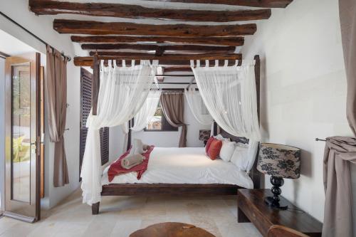 a bedroom with a canopy bed with white curtains at Can Ribes Ibiza in Illes Balears
