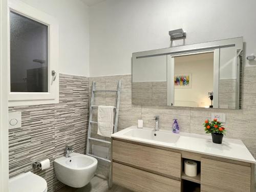 a bathroom with a sink and a toilet and a mirror at IDA PALACE, nuovo appartamento deluxe fronte mare in Stintino