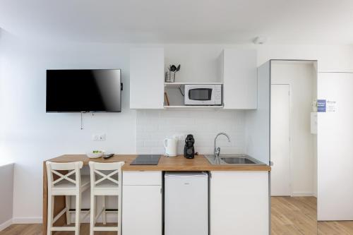 une cuisine avec des armoires blanches, un évier et un micro-ondes dans l'établissement Excalibur, à Brest