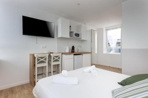 une chambre blanche avec deux lits et une cuisine dans l'établissement Excalibur, à Brest