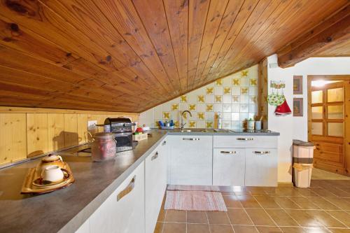 a kitchen with white cabinets and a wooden ceiling at Chez Emilia Mansarda in Aosta