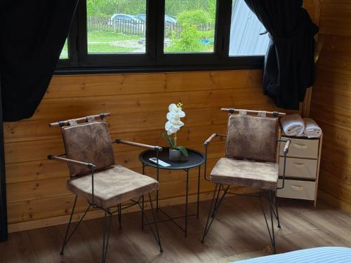 two chairs and a table with a vase of flowers at Thethi Villas in Theth