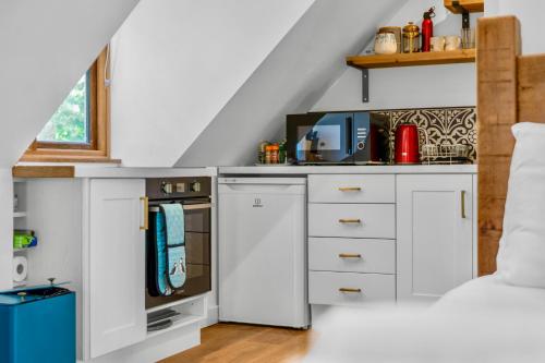 a kitchen with white cabinets and a bed in a room at Edinburgh's Autumn Chalet in Roslin