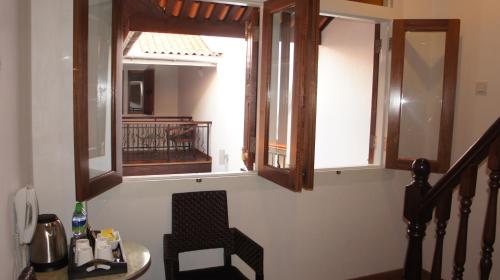 a room with two windows and a table and a chair at Heeren Straits Hotel in Melaka
