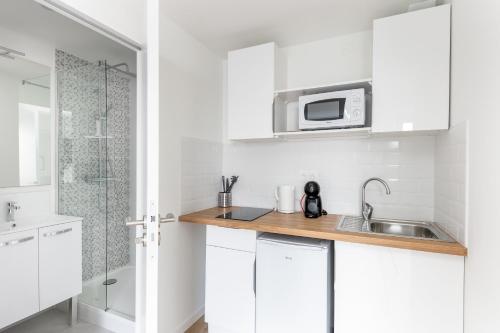 une cuisine blanche avec un évier et un micro-ondes dans l'établissement Viltansou, à Brest