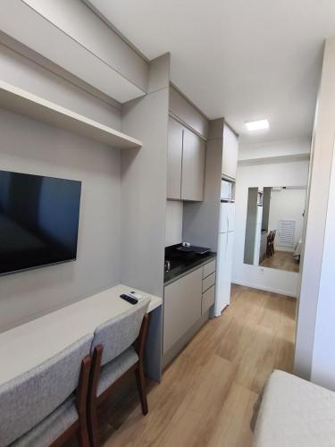 a living room with a kitchen and a table with a television at Studio SUPER LUXO a 5 min do Nubank Parque in São Paulo