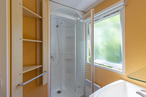 La salle de bains est pourvue d'une douche et d'une fenêtre. dans l'établissement Mobilhome avec terrasse 4 personnes, à Saint-Martial-de-Nabirat