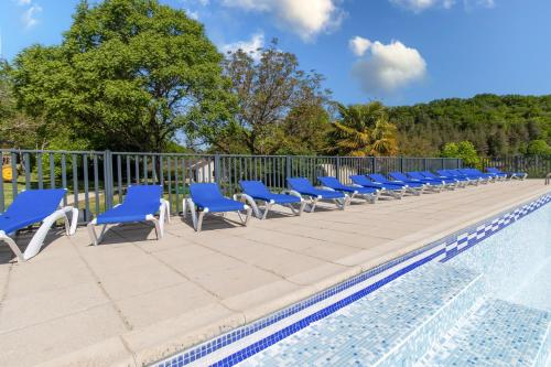 - une rangée de chaises bleues à côté de la piscine dans l'établissement Mobilhome avec terrasse 4 personnes, à Saint-Martial-de-Nabirat