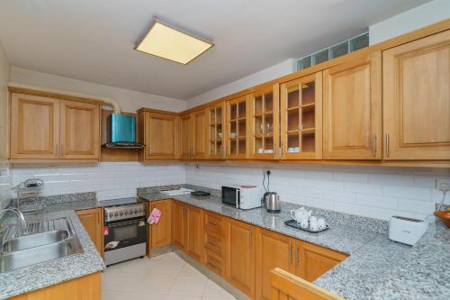 a kitchen with wooden cabinets and granite counter tops at Acacia Green Service Apartments in Kampala