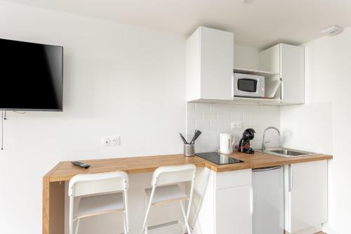 une cuisine avec des armoires blanches et un comptoir avec des tabourets dans l'établissement Korrigan, à Brest