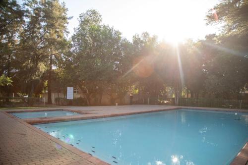 a large blue swimming pool with the sun shining at Apartment in Gaborone in Gaborone