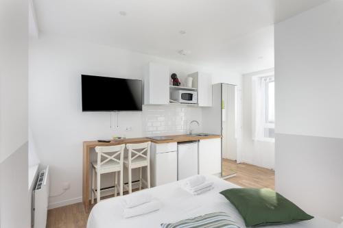 Cette chambre blanche dispose d'un lit et d'une télévision murale. dans l'établissement Merzhin, à Brest