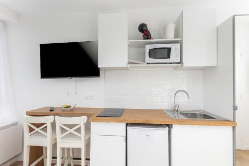 une cuisine blanche avec un évier et un micro-ondes dans l'établissement Merzhin, à Brest