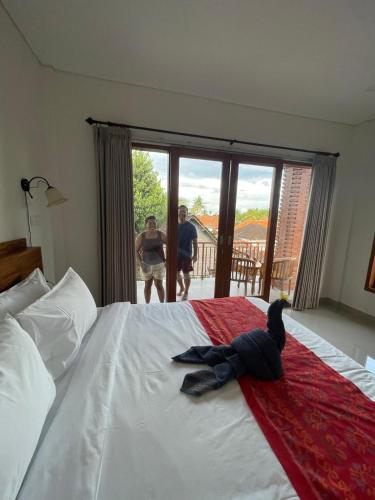 two men standing in a bedroom with a large bed at Umah Arya Homestay & Spa 2 in Gianyar