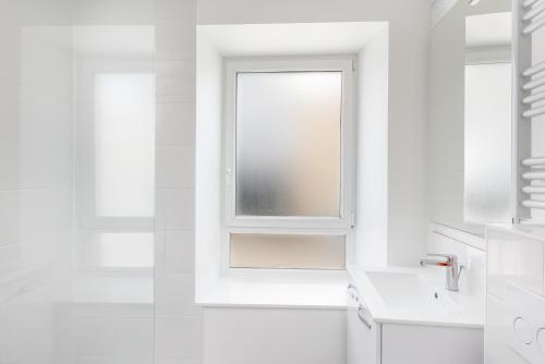 La salle de bains blanche est pourvue d'une fenêtre et d'un lavabo. dans l'établissement Ker'Ys, à Brest