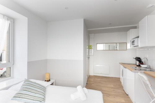 une chambre blanche avec un canapé blanc et une cuisine dans l'établissement Ker'Ys, à Brest