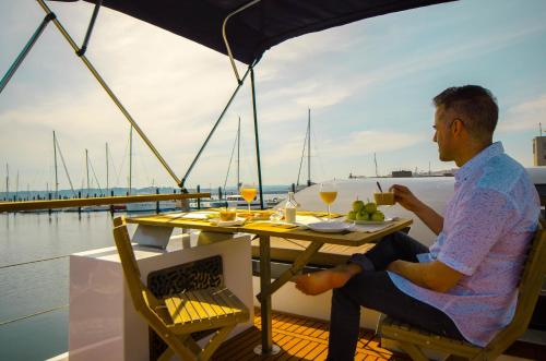 ein Mann, der an einem Tisch auf einem Boot sitzt in der Unterkunft Exclusivas vistas al mar en casa barco, pleno centro, terraza, parking in A Coruña