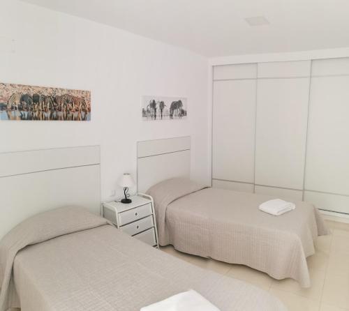 Dos camas en una habitación con paredes blancas. en Residencial Amber III - Apartamento nuevo, amplio y cómodo, en Vecindario