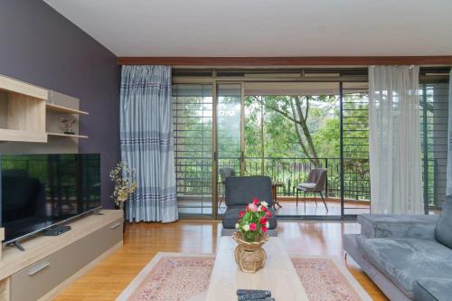 a living room with a couch and a tv at Acacia Green Service Apartments in Kampala
