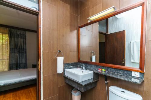a bathroom with a sink and a mirror and a bed at Acacia Green Service Apartments in Kampala