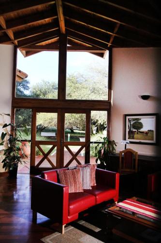 a living room with a red couch and a large window at La Campiña Club Hotel & Spa in Santa Rosa