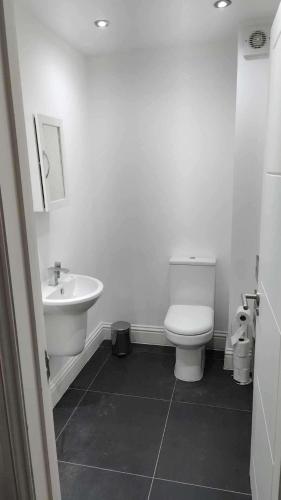 a white bathroom with a toilet and a sink at Spacious 4-Bedroom House - Garden & Free Parking in Faversham