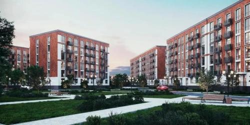 une rangée de bâtiments en briques dans un parc avec des bancs dans l'établissement Buta Fenomen, à Almaty