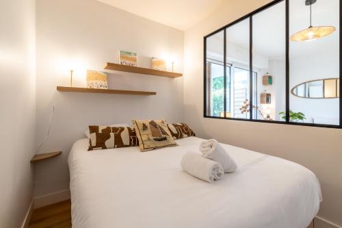 un lit blanc dans une chambre avec une fenêtre dans l'établissement Angelina - studio - parking - wifi, à Vannes