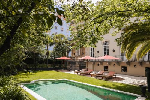 a swimming pool in a yard with chairs and umbrellas at Dear Lisbon - Valmor Palace in Lisbon