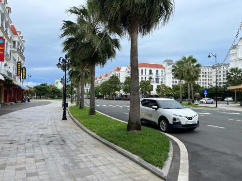 a white car parked next to a street with palm trees at LOCA Hostel Phu Quoc in Phu Quoc