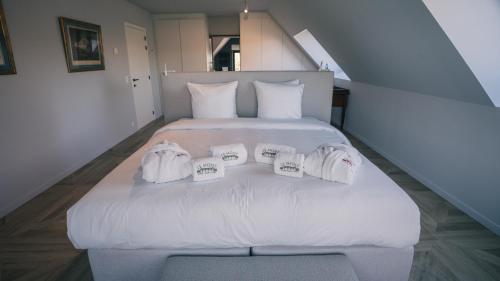 a large white bed with four pillows on it at Gîte - Le Mont in Tournai