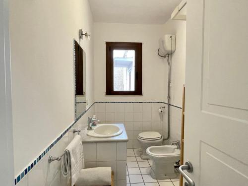 a white bathroom with a sink and a toilet at Appartamento fronte mare nel cuore di Stintino in Stintino