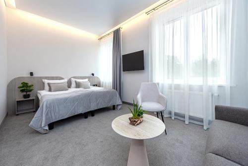a white bedroom with a bed and a couch at Nykščio Namai & SPA in Anykščiai
