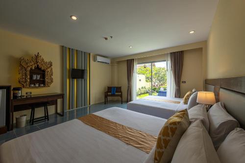a hotel room with two beds and a television at Blue Beach Grand Resort And Spa in Rawai Beach