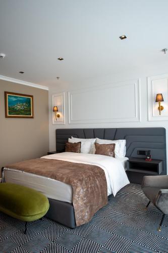 a bedroom with a large bed and a green chair at Sky Airport Hotel in Cluj-Napoca