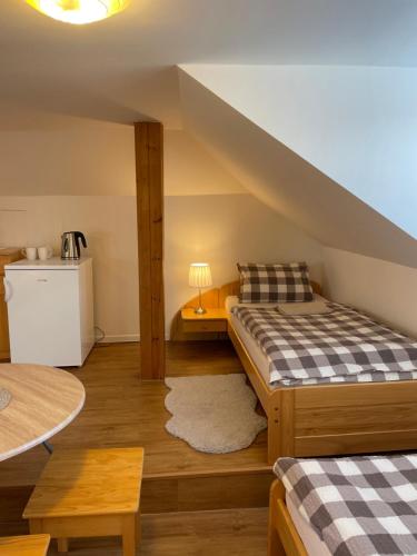 a attic room with two beds and a table at Penzion Ječmínek in Luhačovice
