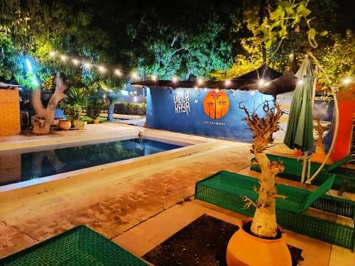 - une piscine avec des lumières et des arbres la nuit dans l'établissement Hôtel Les Palmiers, à Ouagadougou