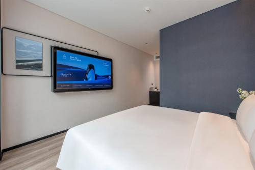 a bedroom with a large white bed and a flat screen tv at Atour Hotel Shenzhen Nanshan Mango Building in Shenzhen