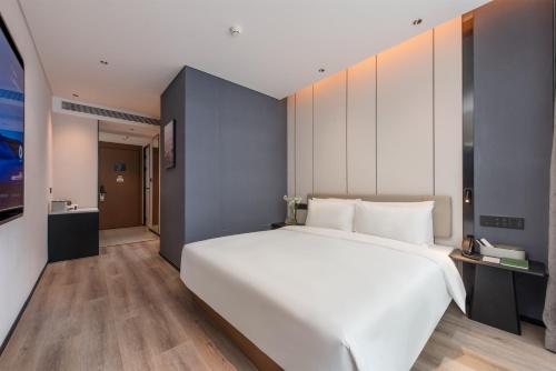 a bedroom with a large white bed and wooden floors at Atour Hotel Shenzhen Nanshan Mango Building in Shenzhen