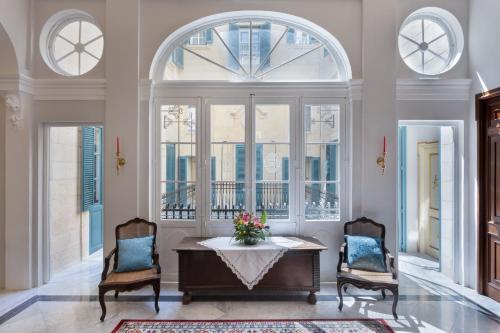 a living room with a table and chairs and windows at Domus Zamittello in Valletta