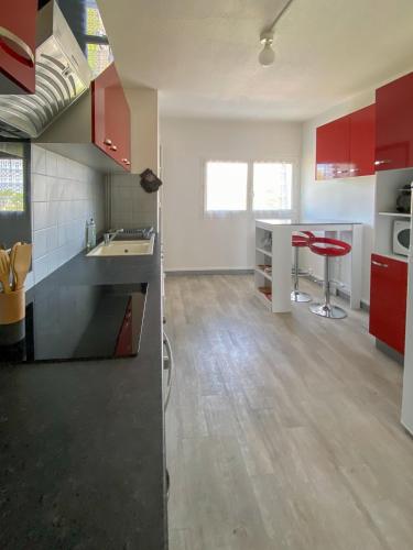 une cuisine vide avec des armoires rouges et des tabourets rouges dans l'établissement Appartement Résidence piscine, à Biscarrosse