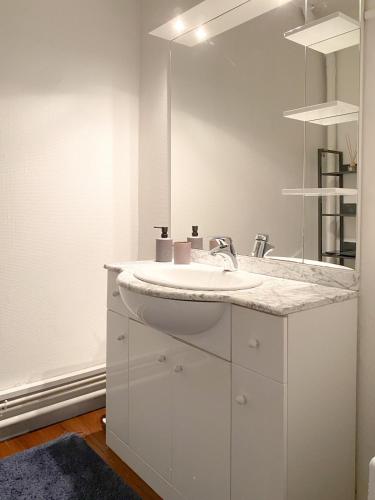 une salle de bain blanche avec un lavabo et un miroir dans l'établissement Appartement Résidence piscine, à Biscarrosse