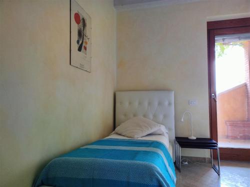 a bedroom with a bed with a blue blanket and a window at IseoLakeRental - Casa Glicine in Sarnico