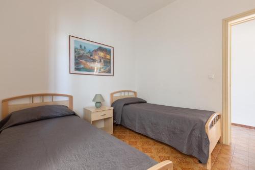 a bedroom with two beds and a picture on the wall at Appartamento Stella Maris by BarbarHouse in Torre dell'Orso