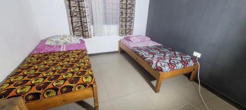 a room with two beds and a chair in it at Lusaka Backpackers in Lusaka