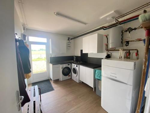 a kitchen with white cabinets and a washing machine at Le gîte des Noës in Lamballe Armor
