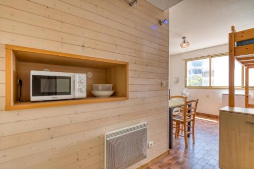 Il comprend une cuisine équipée d'un four micro-ondes et d'une table. dans l'établissement La Grande Motte Studio, à La Grande Motte